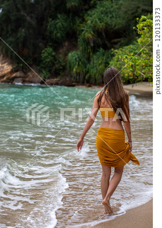 Enjoy a Serene Beach Walk A Woman in a Beautiful Yellow Dress Strolling by the Ocean Shore Enjoy a Serene Beach Walk A Woman in a Beautiful Yellow Dress Strolling by the Ocean Shore 120133373