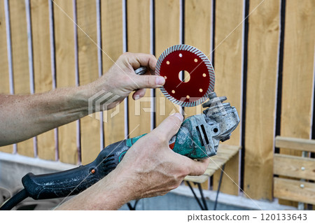 Replaceable diamond blade for cutting stone and concrete is installed on an angle grinder. 120133643