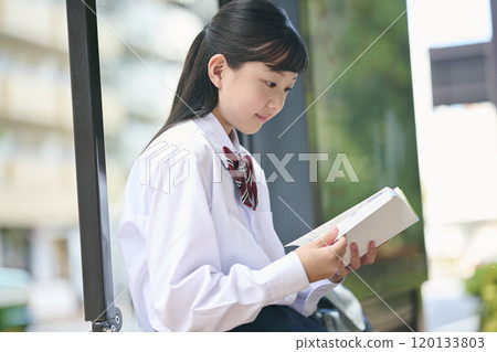 A female junior high school student reading a textbook at a bus stop A female junior high school student reading a textbook at a bus stop 120133803