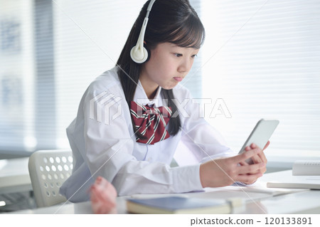 Female junior high school student taking a class on a smartphone 120133891
