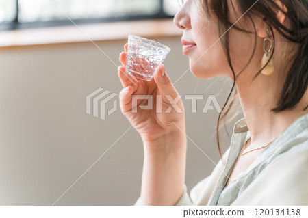 年輕的亞洲女性用冷清酒杯喝日本清酒 年輕的亞洲女性用冷清酒杯喝日本清酒 120134138