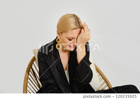 Crying woman sits in a wicker chair 120135025
