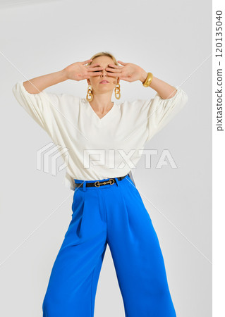 Model showcasing bold blue pants and stylish top in a minimalist studio setting 120135040