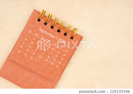 Mini red desk calendar for September 2025 year on old brown paper background. 120135546