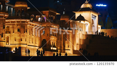 Varanasi, Uttar Pradesh, India. People walking on Lalita Ghat near Kashi Vishwanath Temple complex. Cinematic Camera movement moving along riverbank embankment. View from riverside. night lights 120135970