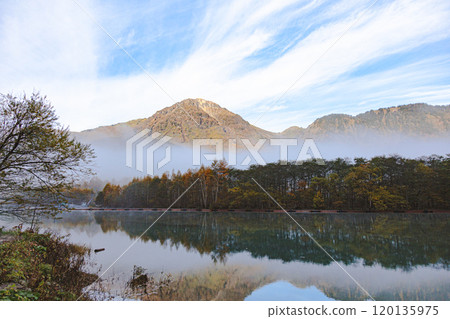 Mount Yakedake bathed in the morning sun as seen from Taisho Pond at dawn in autumn 120135975