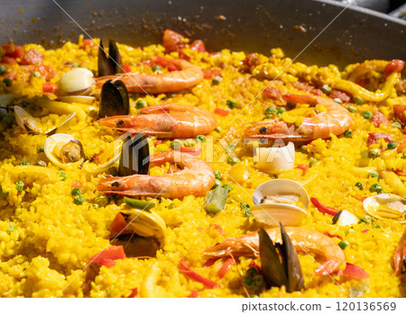 Seafood paella, Spanish rice dish with shrimp, mussels, clams, yellow rice in large pan close up 120136569
