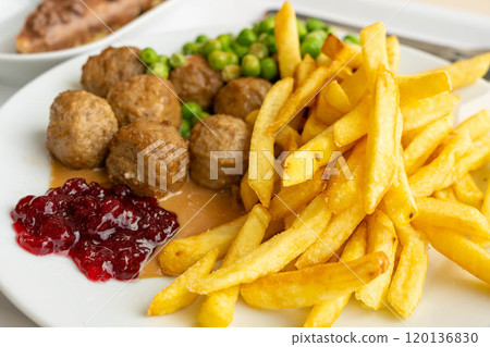 Meatballs with french fries, green peas, bechamel sauce and cranberry jam, meat balls on white plate 120136830