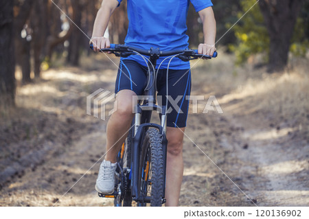 woman cyclist rides in the pine forest on a mountain bike. 120136902