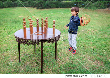 The child is focused on playing, highlighting traditional fun in a natural, green park setting. Recreation and summer fun concepts 120137110