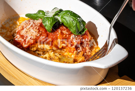 Lasagna portion, oven baked lasagne, pasta layers with cheese, minced meat, tomato in sunny summer day Lasagna portion, oven baked lasagne, pasta layers with cheese, minced meat, tomato in sunny summer day 120137236