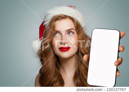 Perfect young smiling woman in red Santa hat showing smartphone Perfect young smiling woman in red Santa hat showing smartphone 120137767