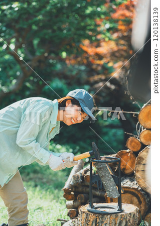 一名婦女將木柴放在切菜台上，然後用錘子敲打它 120138139