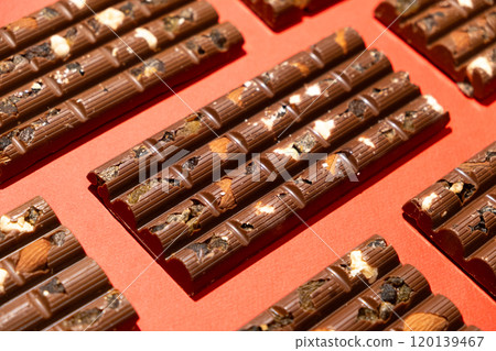 Lots of chocolate bars with nuts and raisins on a red background Lots of chocolate bars with nuts and raisins on a red background 120139467