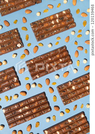 Lots of chocolate bars with nuts and raisins on a blue background top view. 120139468