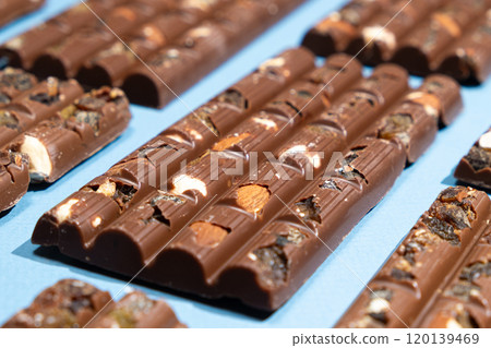 Lots of chocolate bars with nuts and raisins on a blue background 120139469