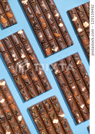 Lots of chocolate bars with nuts and raisins on a blue background top view. 120139492