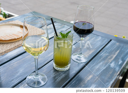 Red wine, herbal lemonade and white wine glasses on restaurant table. Family dinner in restaurant 120139509