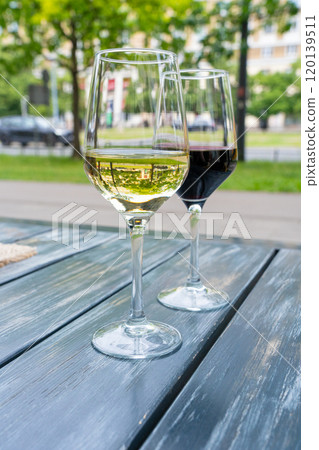 Red wine and white wine glass on restaurant table, wineglasses dinner on restaurant summer terrace 120139511