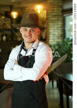 The waiter holds a large raw steak in his hands. Demonstration of steaks in a restaurant. The chef offers a steak in a package. The cook took a steak out of the refrigerator. 120139868