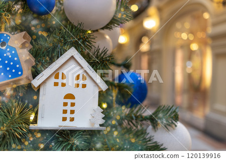 Christmas tree toy in form of house close-up in interior of store. Real estate, mortgage, insurance in New Year Christmas tree toy in form of house close-up in interior of store. Real estate, mortgage, insurance in New Year 120139916