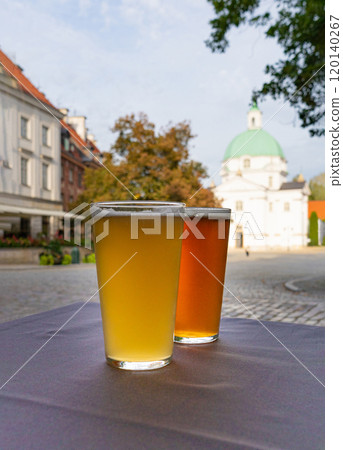 Two glasses of beer, light and dark cold drink on a old European city blurred background, historic buildings 120140267