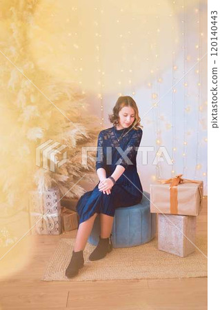 teenage girl in a dress near an unconventional Christmas tree surrounded by golden lights teenage girl in a dress near an unconventional Christmas tree surrounded by golden lights 120140443