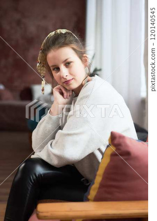 portrait of a teenage girl sitting in a comfortable chair at home, studio photo session 120140545