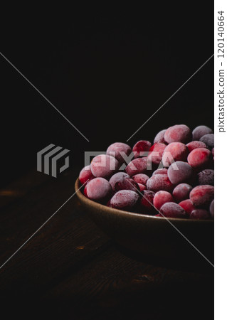 Close up of frozen cranberries in a dark bowl on a dark wooden background 120140664