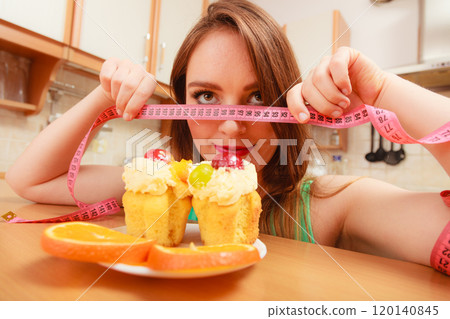 Woman with tape measure and cake. Diet dilemma. 120140845