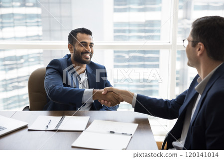 Cheerful young Indian businessman shaking hands with Caucasian business partner 120141014