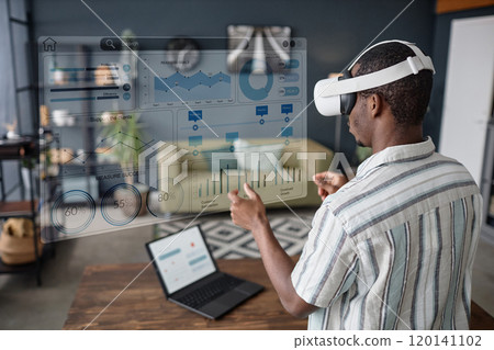Young Black freelancer wearing VR headset standing in living room surfing Internet Young Black freelancer wearing VR headset standing in living room surfing Internet 120141102