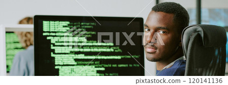 Young African American male cybersecurity specialist sitting at workplace taking off his eyeglasses and looking at camera, website header 120141136