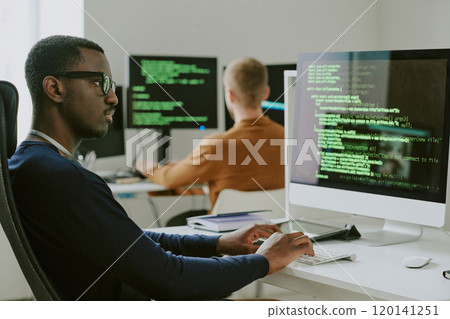 Young African American white-hat hacker checking cybersecurity system on desktop computer in modern office 120141251