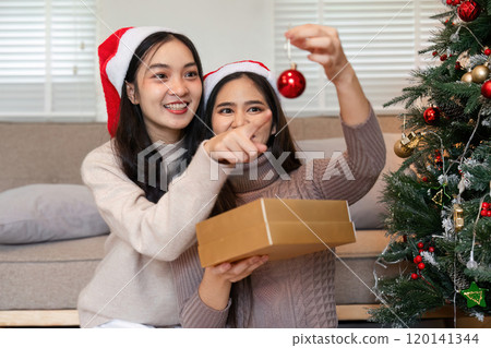 Festive Family Moment: Couple and Young Woman Joyfully Decorating Room for Christmas with Ornaments and Holiday Spirit 120141344