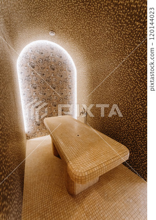 Luxurious spa steam room with tiled massage table and ambient lighting for ultimate relaxation Luxurious spa steam room with tiled massage table and ambient lighting for ultimate relaxation 120144023
