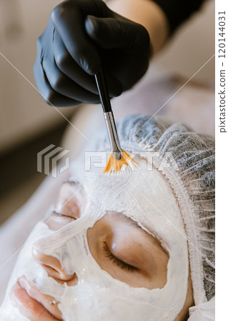Esthetician applying a calming facial mask with a brush for luxurious spa skincare treatment Esthetician applying a calming facial mask with a brush for luxurious spa skincare treatment 120144031