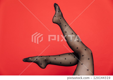 Beautiful female legs in black tights stockings on a red background 120144319