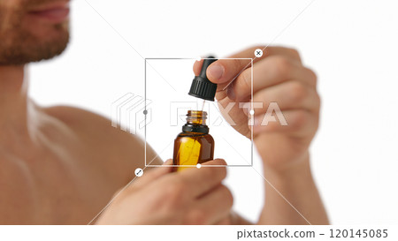 Close-up of man using dropper bottle with serum, representing natural skincare routines for men. Close-up of man using dropper bottle with serum, representing natural skincare routines for men. 120145085