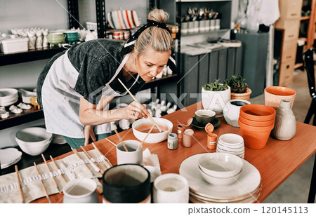 One must have feeling when painting. Cropped shot of an attractive mature woman standing alone and painting a pottery bowl in her workshop. 120145113