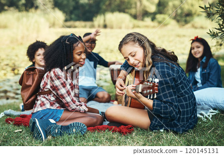 Whats summer camp without a singalong. Shot of a group of teenagers playing musical instruments in nature at summer camp. 120145131
