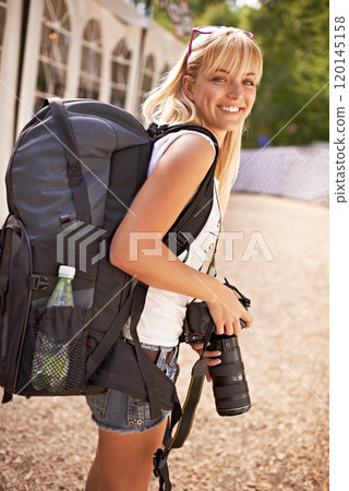 Shes perfectly prepared. A beautiful young photographer walking with gear on her back and camera in her hands. Shes perfectly prepared. A beautiful young photographer walking with gear on her back and camera in her hands. 120145158