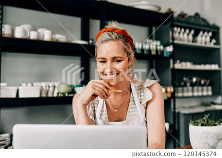 I keep my customers informed through technology. Cropped shot of an attractive mature woman sitting alone and using her laptop in her pottery workshop. 120145374