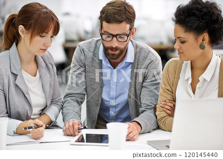 Working through digital paperwork. Shot of a group of young office professionals talking over a digital tablet. 120145440