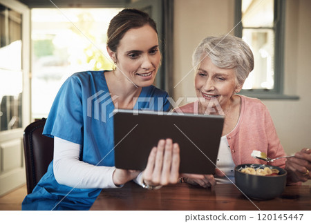 Would you like to send your family a photo. Shot of a young nurse and senior woman using a digital tablet at breakfast time in a nursing home. Would you like to send your family a photo. Shot of a young nurse and senior woman using a digital tablet at breakfast time in a nursing home. 120145447