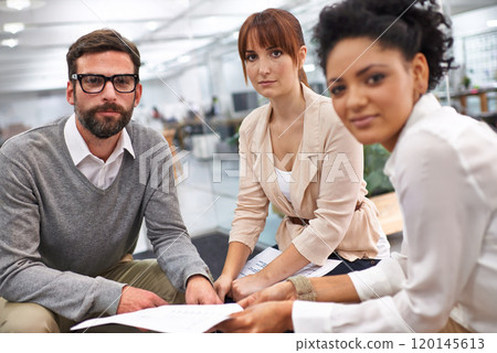 Running through the contracts details. Shot of a group of young professionals discussing paperwork. 120145613