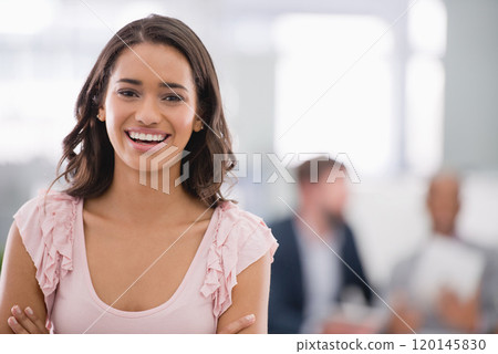 Shes taking this company to the top. Cropped shot of a young businesswoman with her colleagues working in the background. Shes taking this company to the top. Cropped shot of a young businesswoman with her colleagues working in the background. 120145830