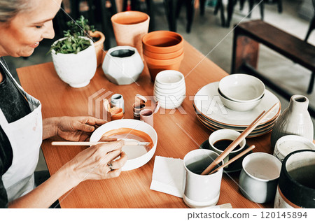 Never be afraid to express yourself. Cropped shot of an attractive mature woman sitting alone and painting a pottery bowl in her studio. 120145894