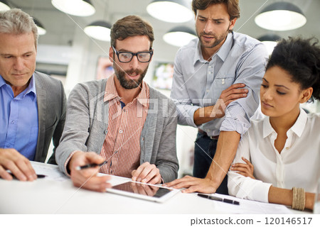 Explaining the teams progress. Shot of a group of young professionals working at a desk in an office. 120146517