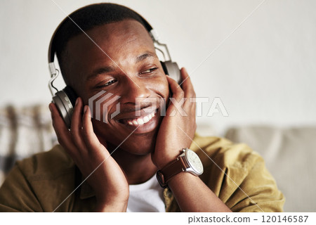 This is a good song right here. Cropped shot of a handsome young man smiling while listening to music on his headphones in his living room at home. This is a good song right here. Cropped shot of a handsome young man smiling while listening to music on his headphones in his living room at home. 120146587